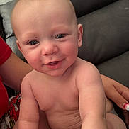 Memphis is registered to the contest to win money with this photo: baby, infant, child, smiling, portrait, sitting, diaper, bare_chested, indoor, couch, sofa, adult_arm, hand, family, face, eyes, happy, cute, close_up, home