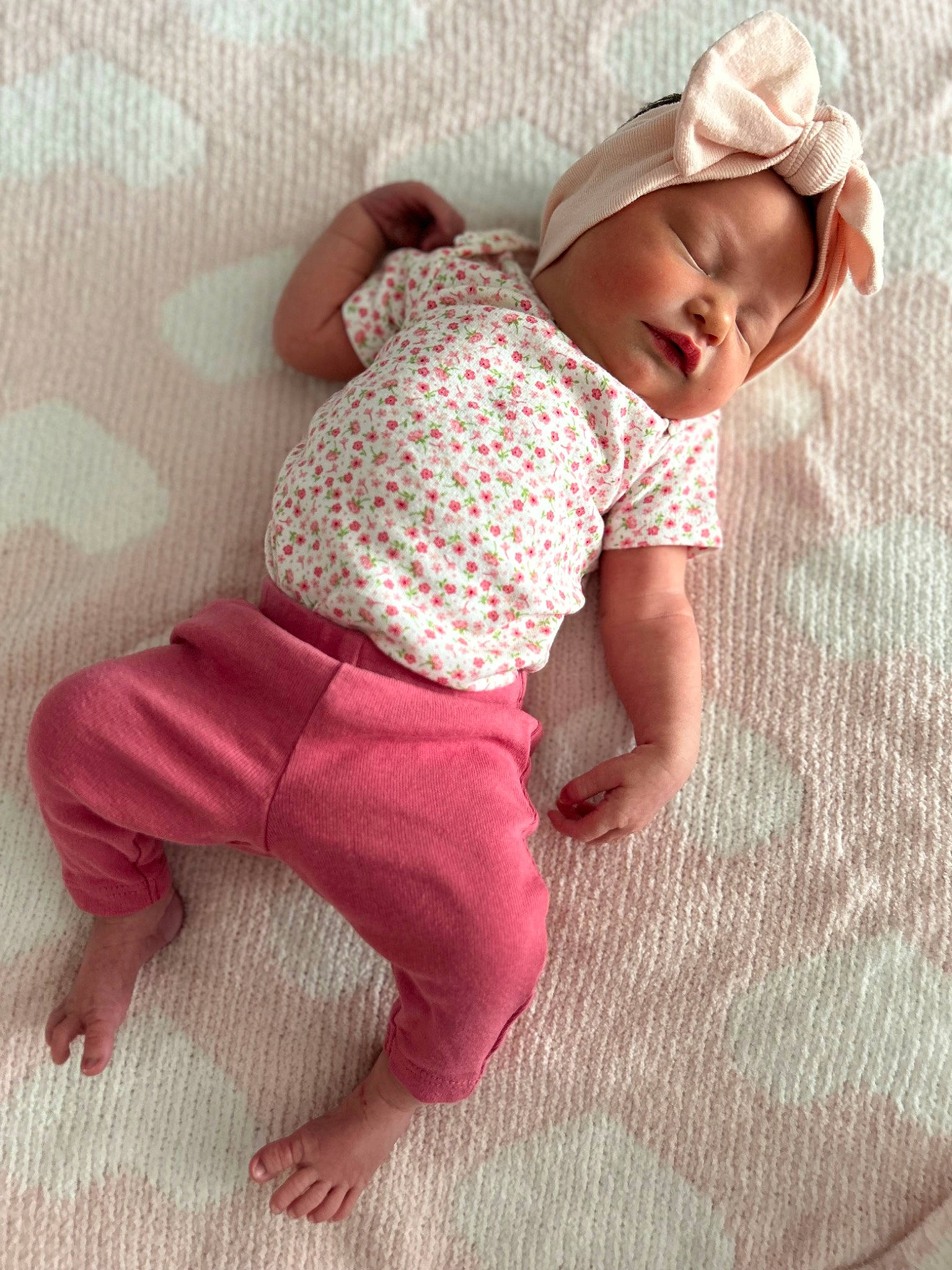 Everly is registered to the contest to win money with this photo: baby, baby_toddler_clothing, cap, child, comfort, eye, face, flooring, head, headgear, human_leg, linens, pattern, person, pink, skin, sleeve, t_shirt, thigh, toddler