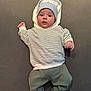 baby, infant, hoodie, striped_sweater, blue_hat, socks, car_pattern, lying_down, grey_background, cute, child, portrait, clothing, casual, indoor, small_hands, face, headwear, comfort, soft_surface