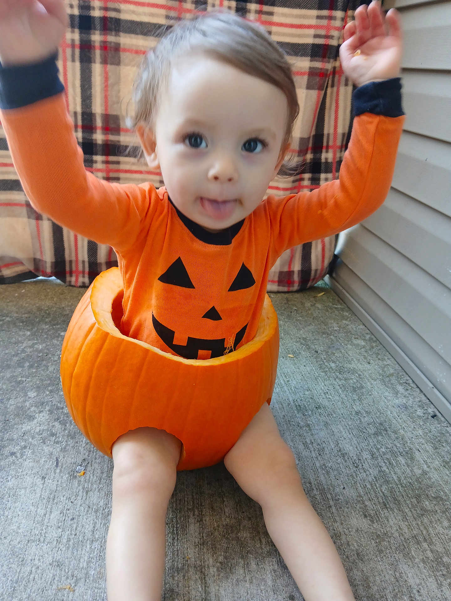 Matteo is registered to the contest to win money with this photo: toddler, child, pumpkin, orange_clothing, costume, halloween, outdoor, concrete, plaid_blanket, cute, baby, face, playful, smile, sitting, legs, hands, tongue, holiday, festive