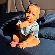 Armando is registered to the contest to win money with this photo: baby, child, infant, bed, bedding, pillow, blanket, blue, sunlight, shadow, skin, face, hand, foot, sitting, clothing, room, headboard, curious, indoors