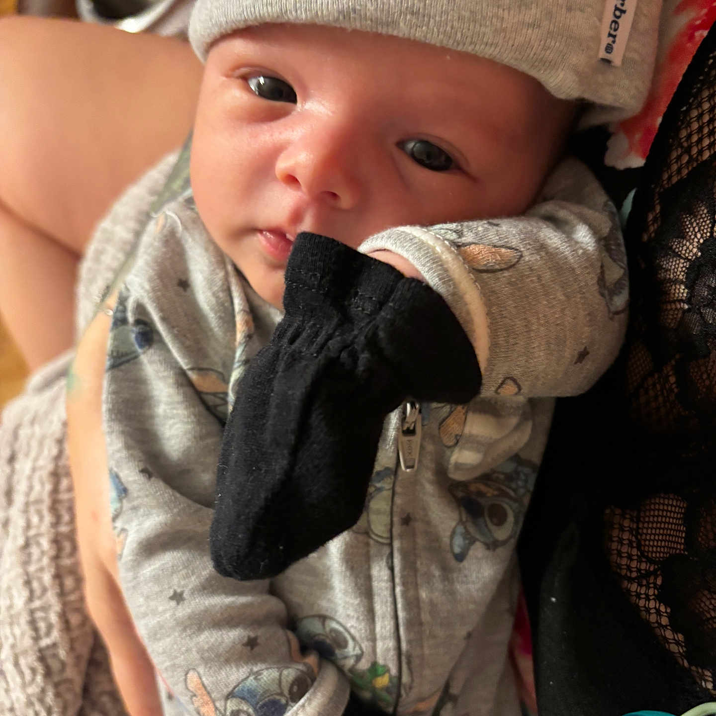 Leonidas is registered to the contest to win money with this photo: apparel, baby, babywear, child, closeup, clothing, cute, fabric, face, hand, hat, holding, indoor, infant, mittens, newborn, person, portrait, skin, soft