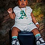 toddler, child, sitting, white_clothing, sneakers, gold_chain, watch, black_ottoman, curious_expression, studio_lighting, portrait, shorts, socks, fashion, cute, indoor, person, footwear, accessories, young_child
