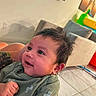 Alexander Jay is registered to the contest to win money with this photo: arm, baby, background, child, clothing, couch, expression, face, floor, hair, happy, home, indoor, infant, person, skin, smile, tattoo, tile, toy
