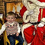 child, boy, santa_claus, christmas, holiday, fireplace, smile, sweater_vest, jeans, white_shoes, yellow_chair, red_suit, gloves, beard, indoor, celebration, festive, bag, happy, portrait
