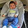 baby, child, infant, portrait, smiling, sitting, bouncer, baby_seat, dinosaur, sweatshirt, blue_pants, white_socks, cartoon, monkey, indoor, home, kitchen, furniture, cozy, happy