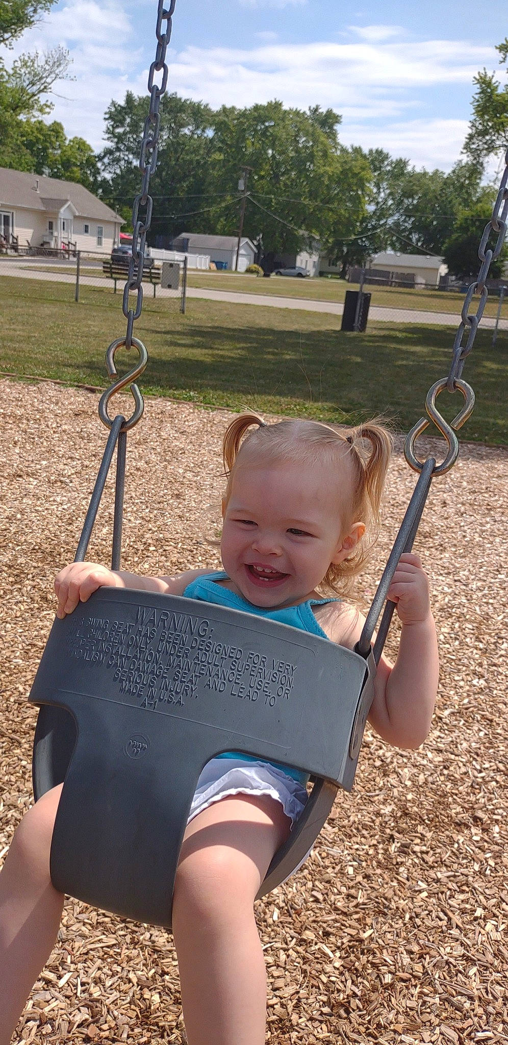 Nova is registered to the contest to win money with this photo: baby, black, child, city, facial_expression, fun, grass, happy, human_settlement, joy, leisure, outdoor_play_equipment, person, plant, playground, recreation, sitting, sky, smile, swing