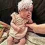 baby, infant, flower_headband, striped_dress, hand, blanket, soft_texture, cute, sitting, child, newborn, skin, fingers, support, cozy, indoors, person, pink, white, comfort