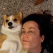 Maple Sue joined the competition — help win amazing prizes! woman, dog, corgi, carpet, lying_down, smile, pet, indoor, face, close_up, brown_hair, white_fur, tan_fur, paw, cute, relaxed, companion, friendship, floor, casual