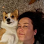 woman, dog, corgi, carpet, lying_down, smile, pet, indoor, face, close_up, brown_hair, white_fur, tan_fur, paw, cute, relaxed, companion, friendship, floor, casual
