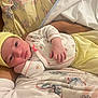 baby, infant, person, clothing, yellow_hat, yellow_pants, floral_pattern, arm, hand, blanket, fabric, resting, indoor, soft_lighting, cute, newborn, closeup, portrait, young_child, comfort