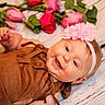 baby, brown_outfit, child, close_up, cute, flower, flower_headband, happy, headband, indoors, infant, lying_down, person, pink_flowers, portrait, red_flowers, roses, skin, smile, wooden_floor