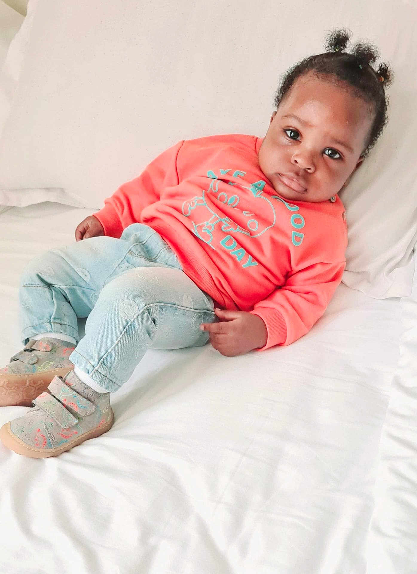 Oluwajomiloju is registered to the contest to win money with this photo: baby, child, infant, bed, clothing, sweatshirt, denim, pants, shoes, hair, face, skin, indoor, portrait, cute, cozy, white_bed, lying_down, expression, casual