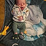 baby, infant, smiling, blanket, elephant, clothing, dinosaur, slippers, cute, lying_down, cozy, soft, child, portrait, happy, young, indoor, person, animal_print, warm