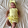 baby, child, smiling, yellow_outfit, headband, lying_down, blanket, white_socks, cute, happy, infant, soft_texture, portrait, indoors, one_person, young_child, skin, clothing, baby_fashion, relaxed