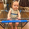 baby, shopping_cart, child, store, retail, clothing, rack, floor, bow, girl, barefoot, walmart, curious, shopping, aisle, infant, seated, handle, expression, casual