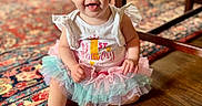 Lorraine joined the competition — help win amazing prizes! baby, child, tutu, birthday, smile, happy, sitting, floor, wooden_floor, indoor, clothing, girl, person, face, eyes, arm, hand, colorful, home, furniture