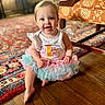baby, child, tutu, birthday, smile, happy, sitting, floor, wooden_floor, indoor, clothing, girl, person, face, eyes, arm, hand, colorful, home, furniture