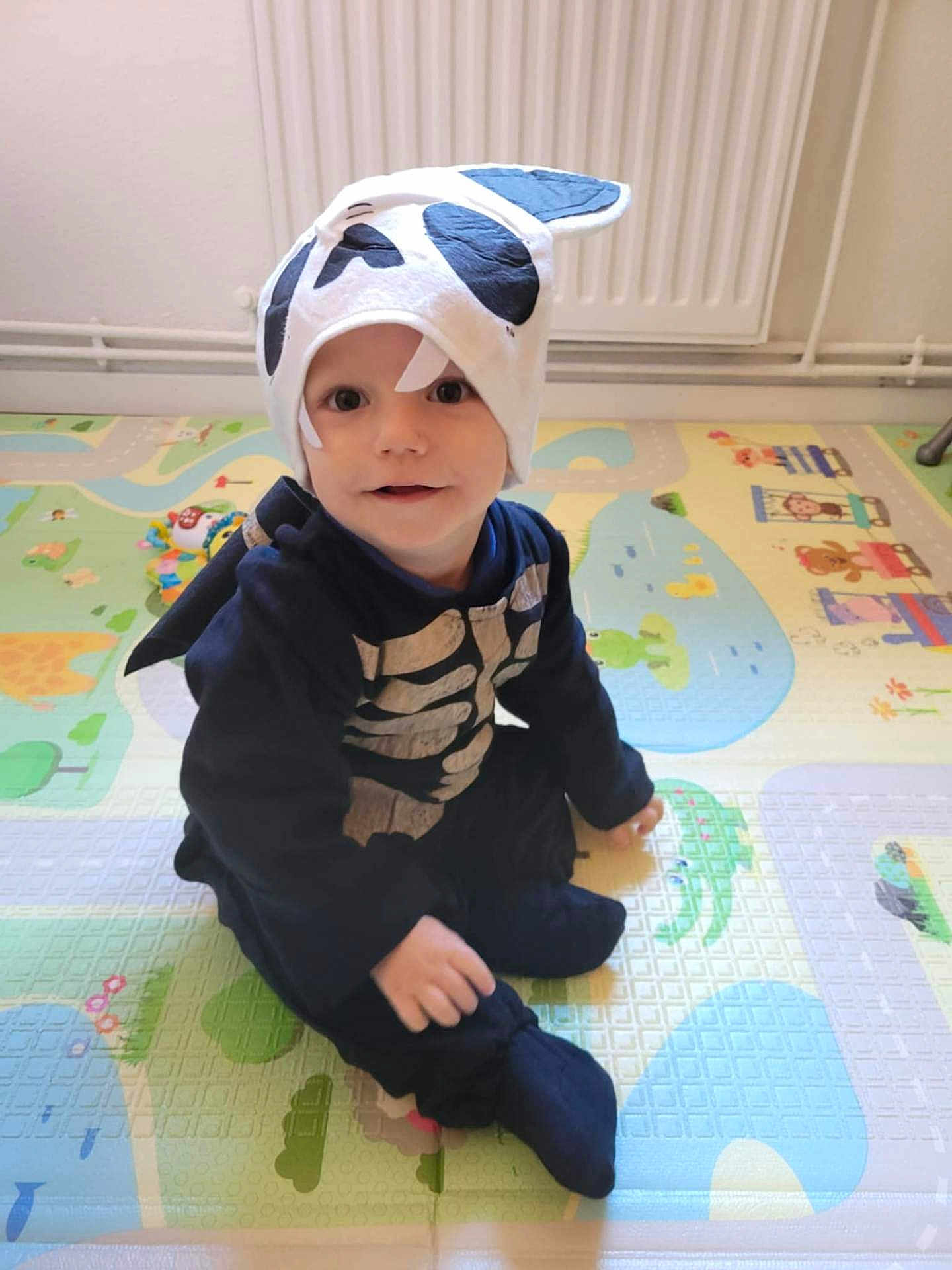 Aaron Kieffer participe au concours pour gagner de l'argent avec cette photo : baby, child, clothing, costume, cute, face, floor, hat, headwear, indoor, infant, play_mat, playtime, portrait, sitting, skeleton, smile, toddler, toy, young_child
