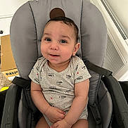 Liam participe au concours pour gagner de l'argent avec cette photo : baby, child, clothing, cute, eyes, face, furniture, gray_chair, hair, hands, happy, indoor, infant, light_gray, onesie, person, radiator, seated, smiling, young_child