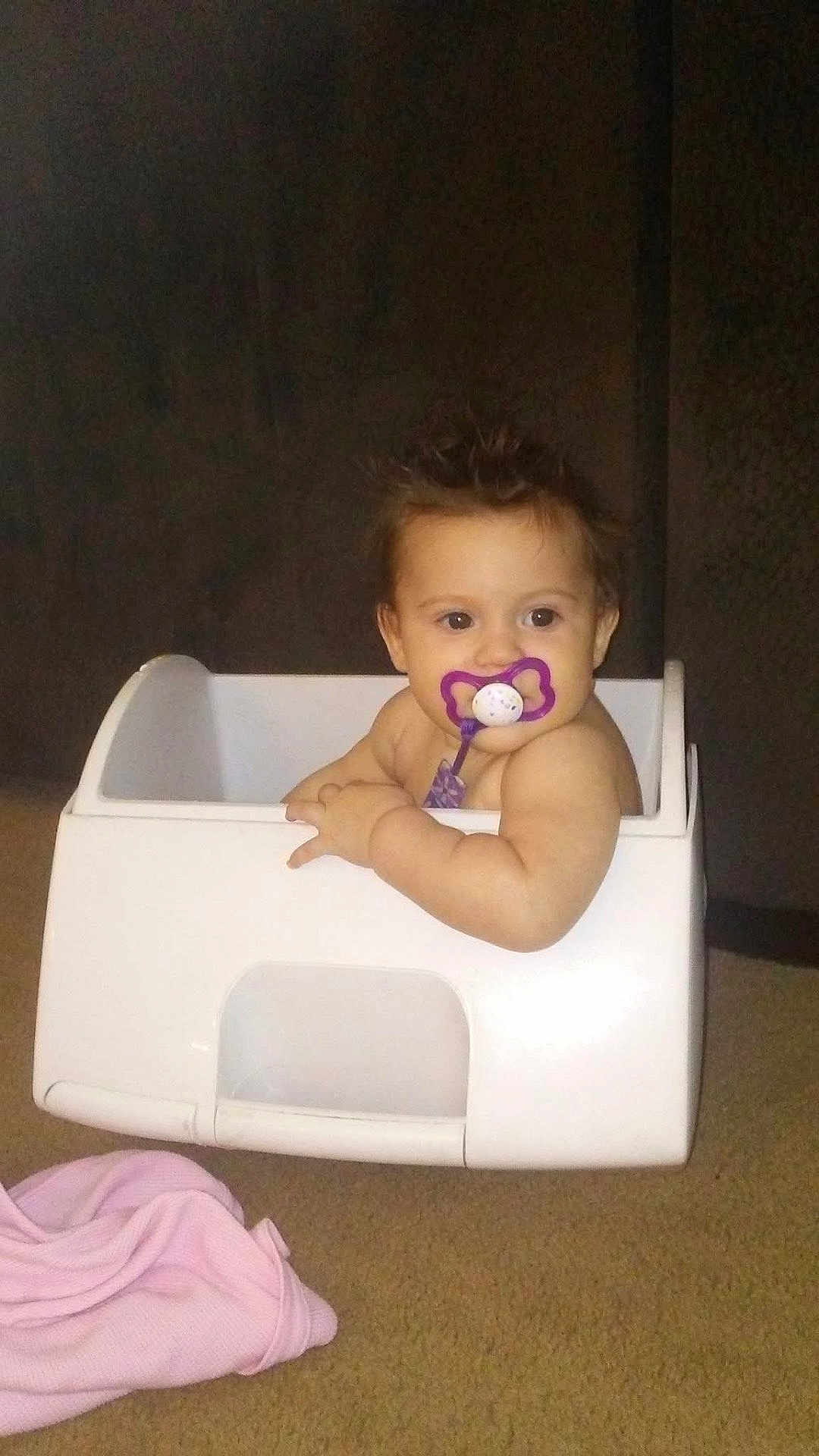 Faith joined the competition — help win amazing prizes! baby, infant, pacifier, plastic_box, storage_container, carpet, pink_blanket, indoor, dark_background, spiky_hair, chubby_cheeks, arm, face, eyes, sitting, cute, portrait, toddler, playtime, furniture