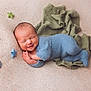 newborn, baby, smiling, knitted_outfit, blue_clothing, soft_blanket, felt_stars, green_cloth, sleeping, peaceful, infant, cute, portrait, cozy, hands_together, head, face, lying_down, warm_colors, indoor