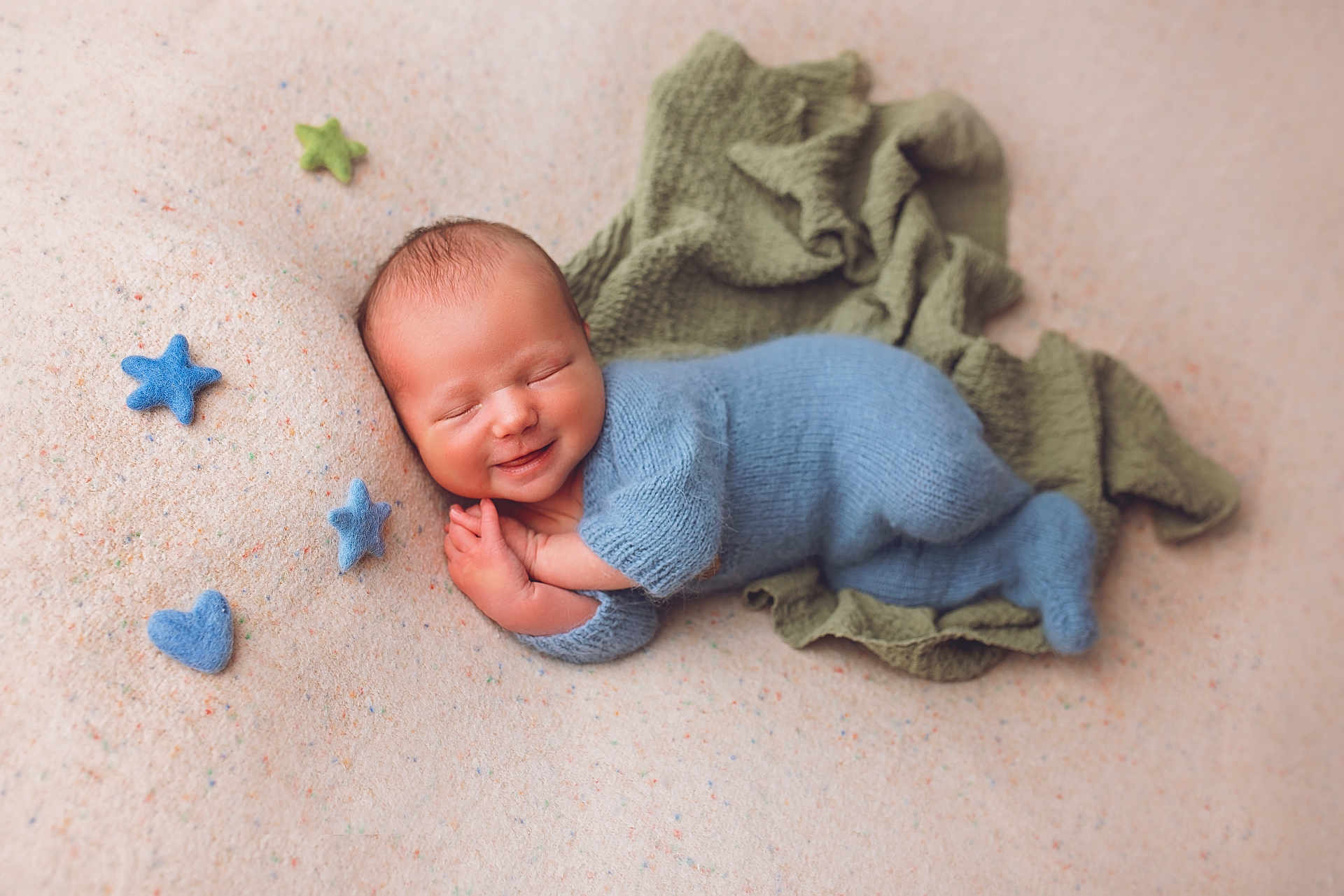 Emil joined the competition — help win amazing prizes! newborn, baby, smiling, knitted_outfit, blue_clothing, soft_blanket, felt_stars, green_cloth, sleeping, peaceful, infant, cute, portrait, cozy, hands_together, head, face, lying_down, warm_colors, indoor