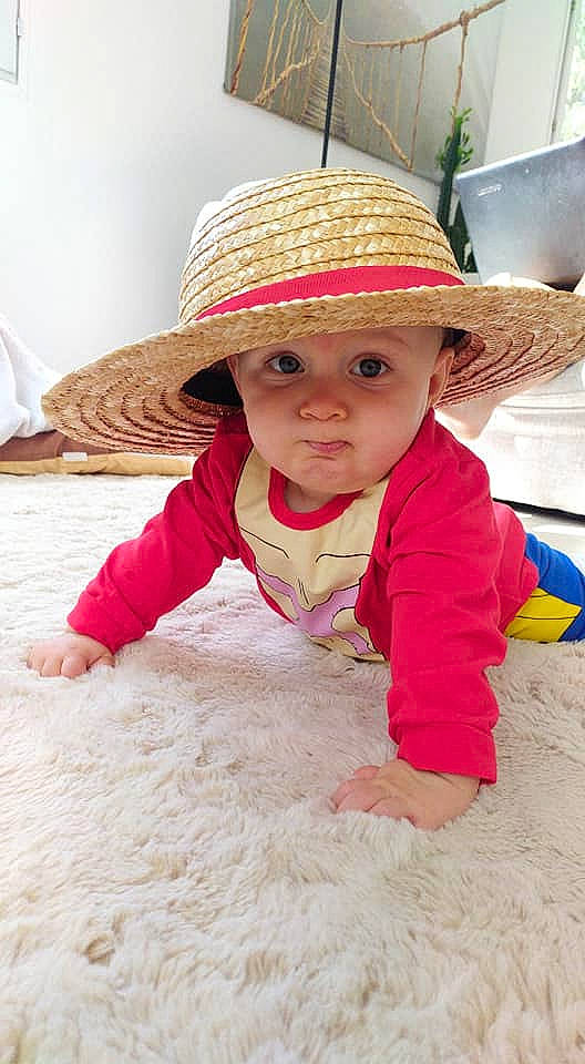 Izaya participe au concours pour gagner de l'argent avec cette photo : baby, baby_toddler_clothing, child, fashion_accessory, flooring, fun, happy, hat, headgear, headwear, leisure, person, play, portrait_photography, sand, sleeve, smile, soil, sun_hat, toddler