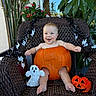 baby, pumpkin, halloween, wicker_chair, ghost_decoration, jack_o_lantern, plants, greenery, smiling, happy, holiday, costume, decoration, cute, festive, autumn, child, outdoor, seat, holiday_spirit