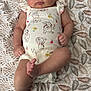 baby, infant, onesie, cartoon_print, blanket, leaf_pattern, cute, child, laying_down, skin, foot, hand, face, expression, indoors, sleepwear, soft_lighting, plush, young, resting