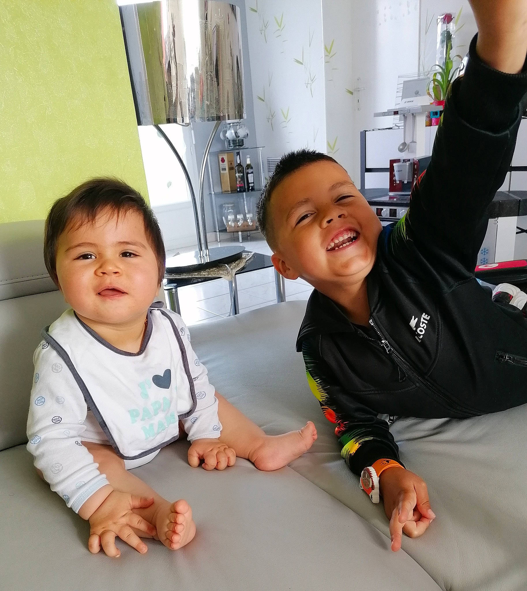 Kélyo participe au concours pour gagner de l'argent avec cette photo : baby, baby_toddler_clothing, child, floor, flooring, fun, gesture, happy, joy, kitchen, kitchen_appliance, person, room, service, shorts, sitting, skin, sleeve, smile, t_shirt