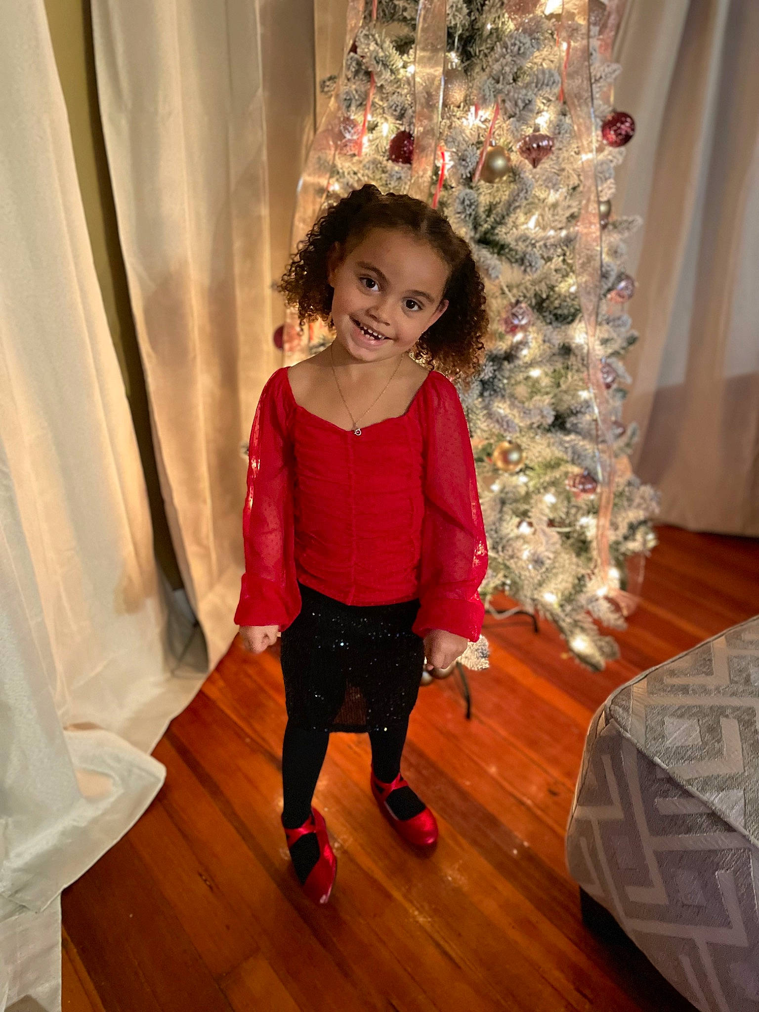 Elaina is registered to the contest to win money with this photo: baby_toddler_clothing, christmas_decoration, christmas_ornament, christmas_tree, curtain, event, face, flooring, fun, happy, hardwood, joy, ornament, person, pink, sleeve, smile, standing, toddler, tree