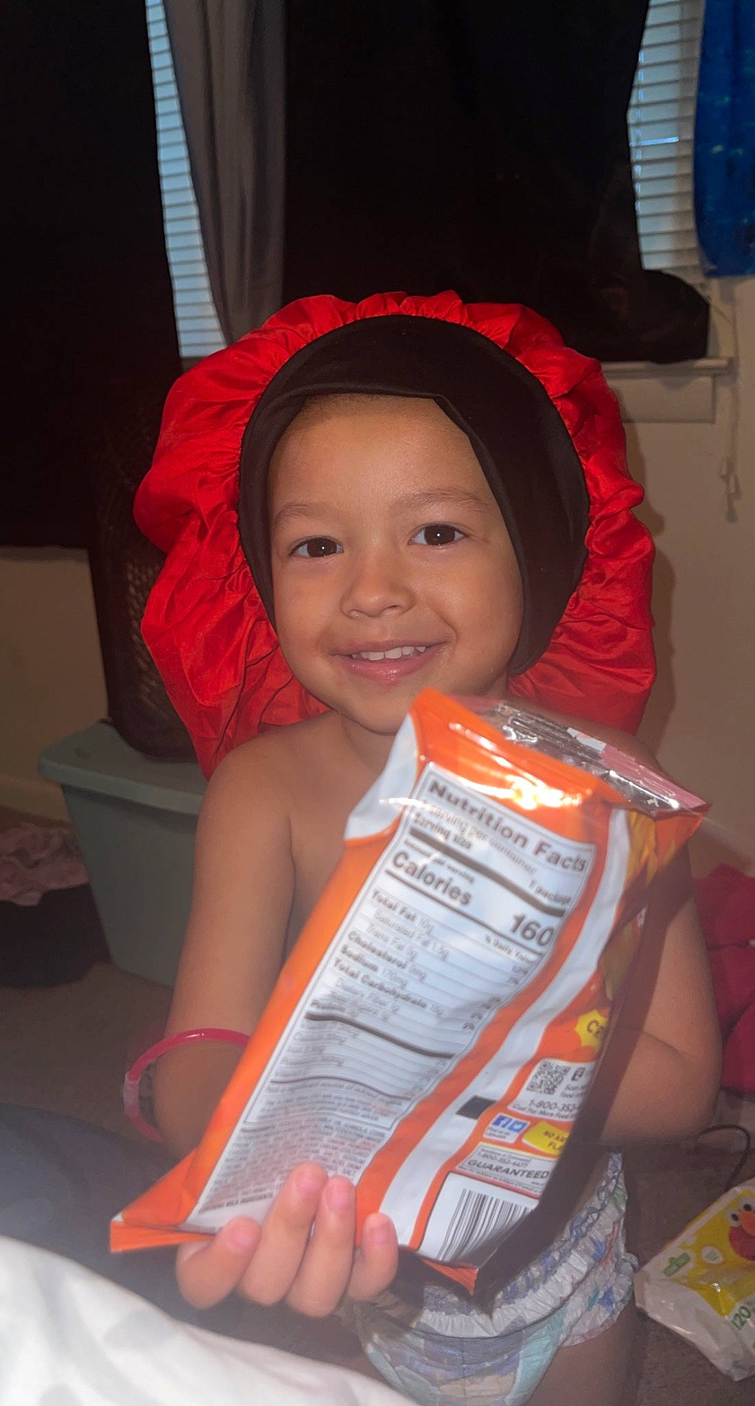 Zaiden is registered to the contest to win money with this photo: carmine, child, chin, fashion_accessory, fun, happy, human_body, joy, magenta, organ, person, reading, red, room, sitting, smile, toddler, vacation