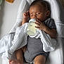 baby, infant, bottle, feeding, sleeping, blanket, striped_clothing, onesie, cushion, white, soft, peaceful, indoors, child, resting, hand, foot, face, head, comfort
