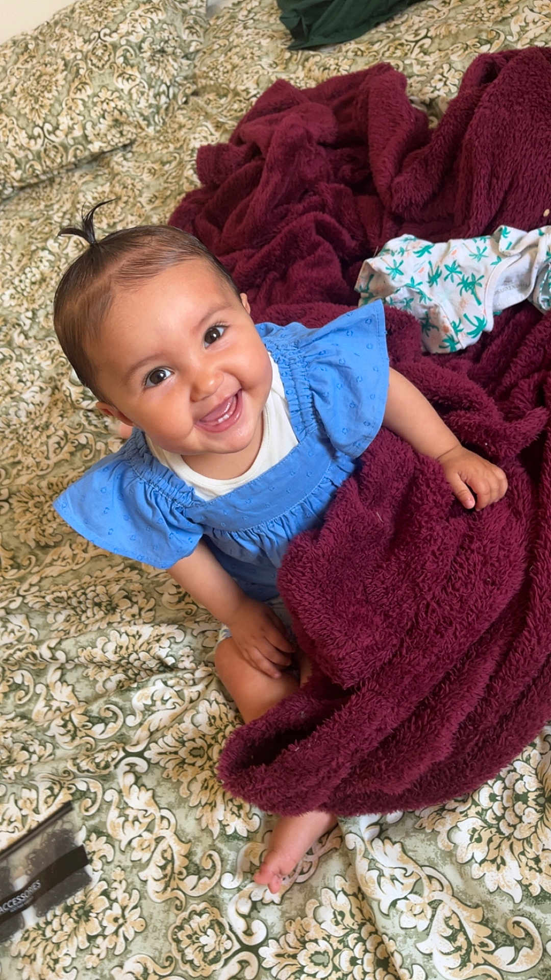 Naïla a rejoint le concours — aidez-le/la à gagner de superbes lots ! baby, smiling, blue_dress, blanket, bedspread, patterned, indoors, child, happy, cute, person, infant, face, hair, skin, foot, hand, sitting, cozy, warm