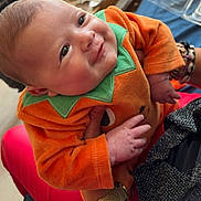 Keyliah a rejoint le concours — aidez-le/la à gagner de superbes lots ! baby, infant, child, smiling, orange_clothing, green_accent, hands, adult, closeup, face, cute, portrait, indoor, soft_light, holding, joy, happy, skin, person, apparel