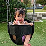 toddler, child, swing, playground, outdoor, grass, greenery, park, baby, cute, hair_ties, black_swing, foot, holding, expression, nature, urban_background, daylight, person, recreation