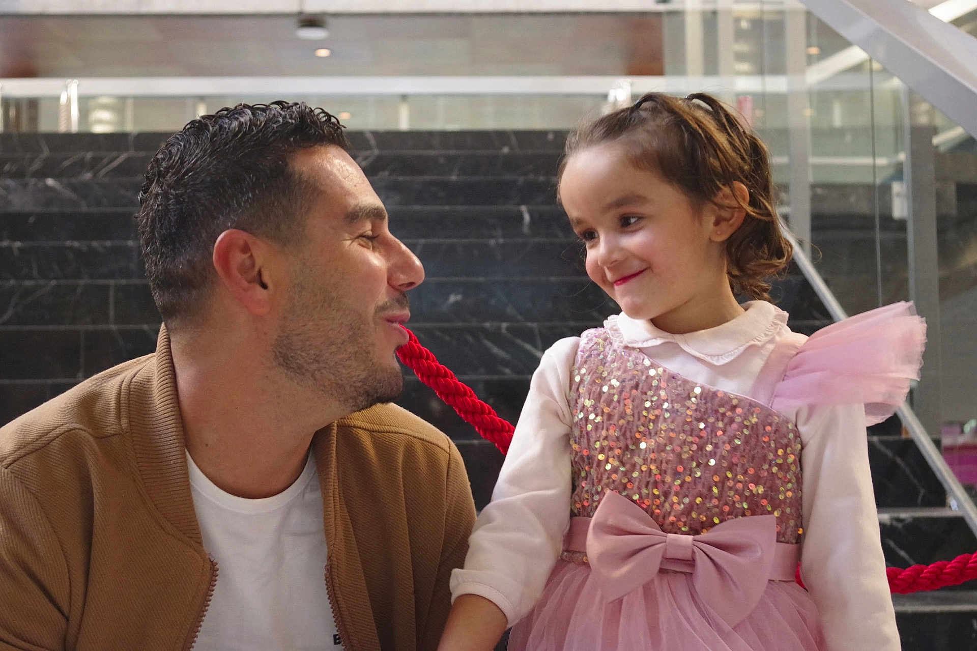Eileen participe au concours pour gagner de l'argent avec cette photo : man, child, girl, smile, dress, pink, bow, rope, interaction, stairs, marble, indoor, happy, family, people, casual_clothing, glass, railing, portrait, playful