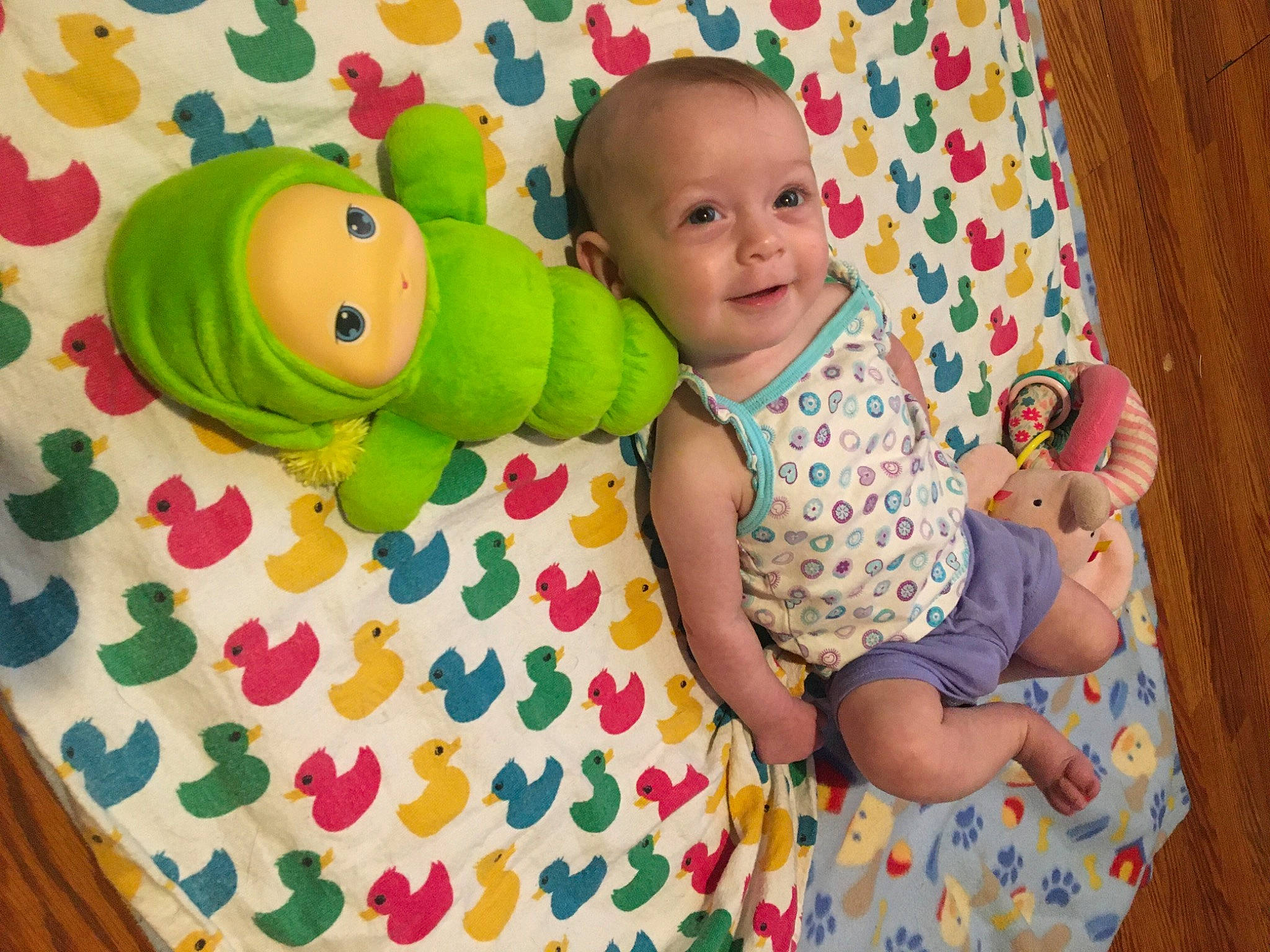 Jada is registered to the contest to win money with this photo: baby, baby_playing_with_toys, baby_products, baby_toddler_clothing, child, comfort, face, facial_expression, fun, green, happy, head, linens, pattern, person, product, room, smile, textile, toddler