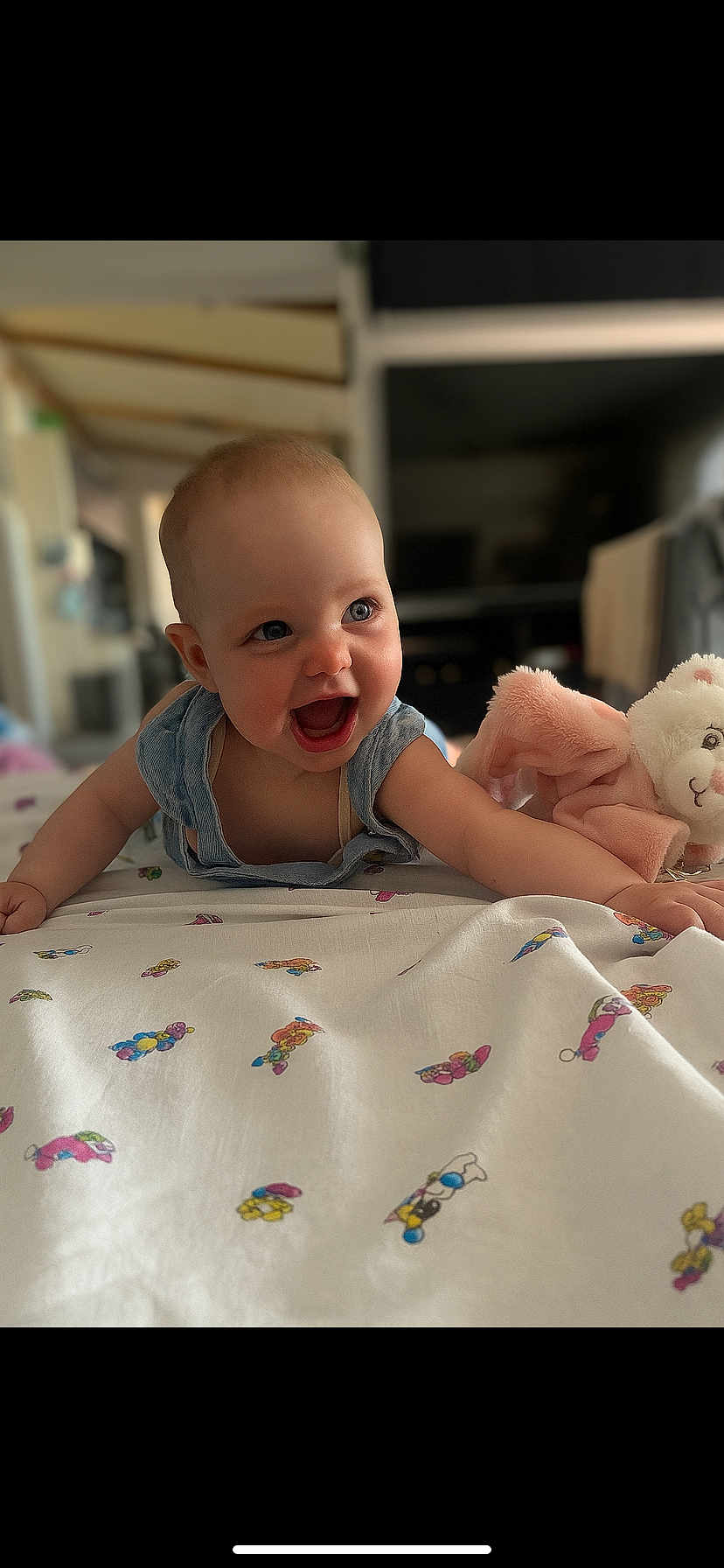 Lya participe au concours pour gagner de l'argent avec cette photo : baby, child, smiling, happy, indoor, blanket, stuffed_animal, toy, face, expression, cute, infant, clothing, blue, skin, person, portrait, mouth_open, lying_down, playful