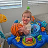 Caysen joined the competition — help win amazing prizes! baby, child, smiling, basketball, toy, activity_walker, indoor, portrait, sitting, playtime, colorful, infant, face, hands, living_room, window_blinds, sofa, plastic_toys, happy, sports