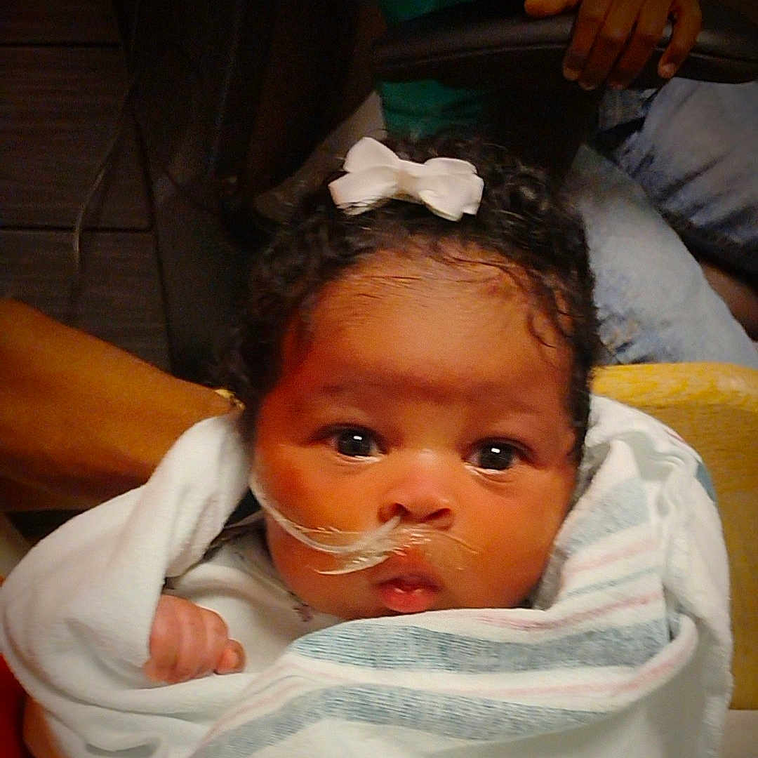 Nova joined the competition — help win amazing prizes! baby, blanket, bow, child, comfort, curly_hair, cute, expression, face, healthcare, holding, indoor, infant, nasal_tube, newborn, person, skin, wide_eyes, wrapped, young