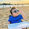 baby, sunglasses, blue_clothing, beach, sand, sunset, baby_chair, child, outdoor, summer, sunlight, cute, portrait, footwear, person, infant, vacation, relaxation, sunshine, fun