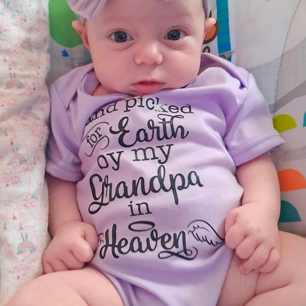Leanna Mae joined the competition — help win amazing prizes! baby, blanket, bow, close_up, cute, eyes, face, hands, headband, indoor, infant, legs, nursery, onesie, pattern, portrait, purple, sitting, soft_toys, text_on_clothing