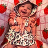 baby, infant, child, smiling, happy, portrait, hood, dress, frills, cow_print, strawberry_blanket, pink, coral, lying_down, indoor, close_up, face, eyes, baby_clothing, cute