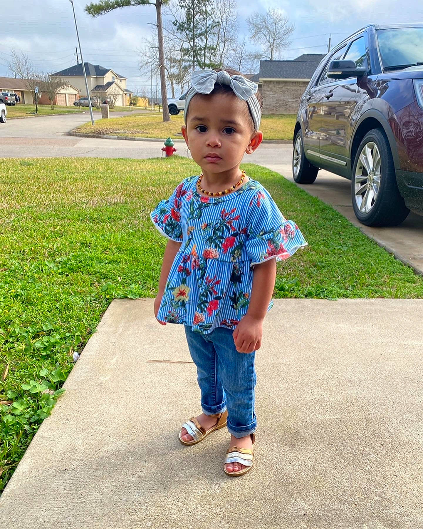 Gianna is registered to the contest to win money with this photo: asphalt, automotive_tire, car, electric_blue, grass, landscape, leisure, motor_vehicle, person, plant, recreation, road, sky, summer, t_shirt, tire, toddler, tree, vehicle, vehicle_door