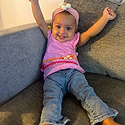 Aria is registered to the contest to win money with this photo: baby, child, smile, happy, couch, jeans, headband, pink, arms_up, indoor, person, clothing, barefoot, cute, infant, sitting, furniture, portrait, joyful, casual