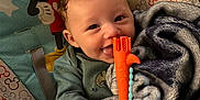 Dempsey is registered to the contest to win money with this photo: baby, child, smiling, blanket, toy, teething_toy, mickey_mouse, seat, curly_hair, happy, indoor, infant, clothing, person, cute, playful, comfort, colorful, young_child, portrait