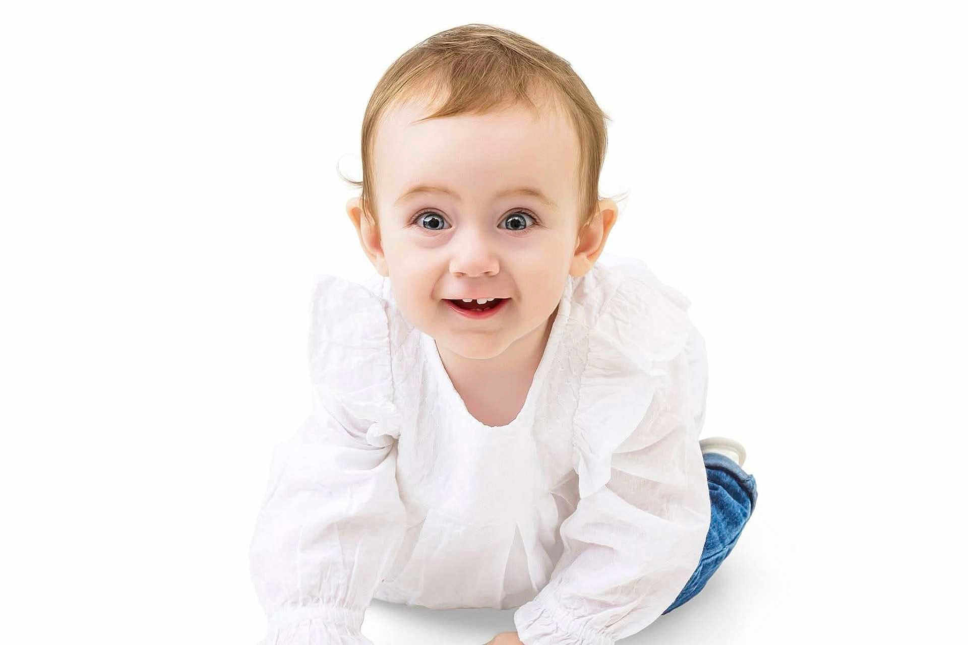 Josie is registered to the contest to win money with this photo: baby, child, smile, crawling, white_blouse, blue_jeans, happy, cute, infant, portrait, studio, bright, eyes, hair, hands, floor, white_background, clothing, person, closeup