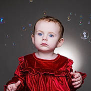 Josie is registered to the contest to win money with this photo: child, toddler, baby, blue_eyes, red_dress, velvet, bubbles, studio_lighting, portrait, curious, hands, soft_light, indoor, innocent, cute, fashion, young_child, face, expression, studio_background